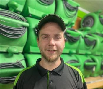 employee in black polo against a green background