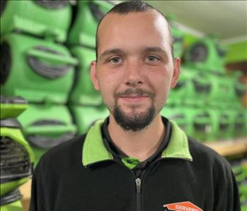 employee in a black polo against a green background