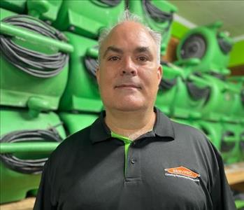 employee in a black polo against a green background